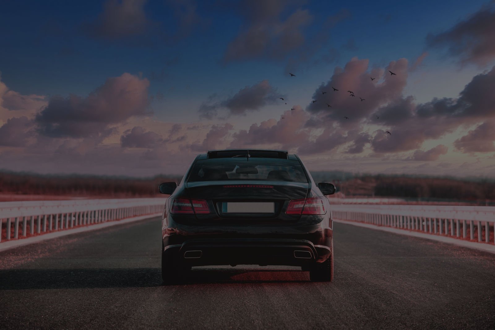 Luxurious black car riding in the street with a beautiful sky